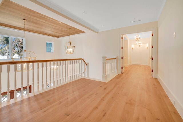 unfurnished room featuring an inviting chandelier, ornamental molding, and light wood-type flooring