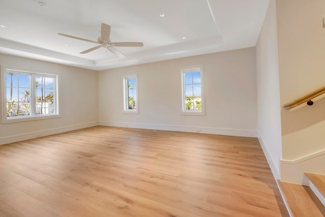 spare room with a raised ceiling, ceiling fan, and light wood-type flooring