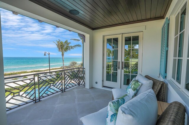 view of pool featuring a beach view, a water view, and a patio