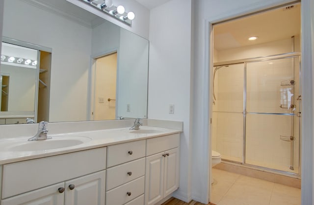 bathroom with toilet, double sink, an enclosed shower, tile flooring, and large vanity