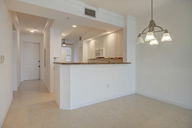 kitchen with pendant lighting, light tile floors, white cabinetry, and ceiling fan with notable chandelier