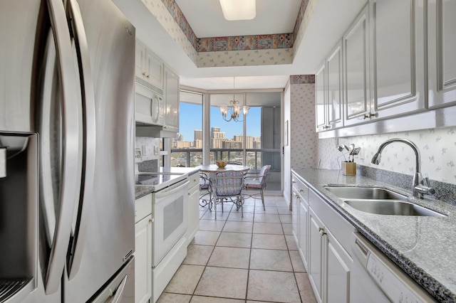 kitchen featuring hanging light fixtures, white appliances, a notable chandelier, sink, and white cabinets