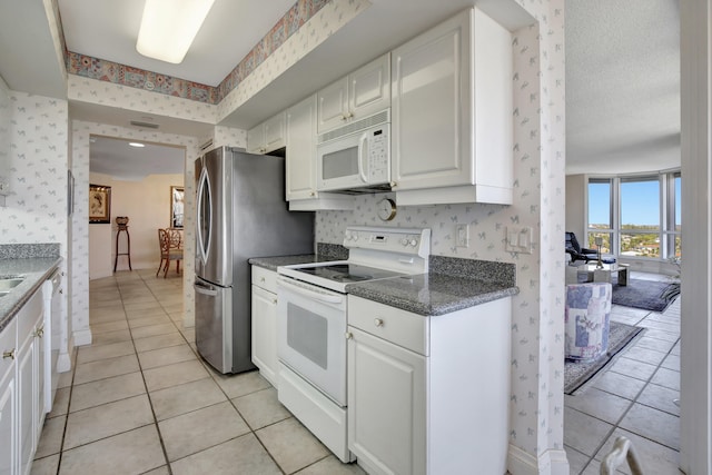 kitchen with white appliances, light tile flooring, and white cabinets