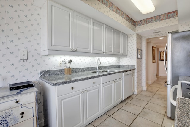 kitchen with sink, light tile floors, white dishwasher, range, and white cabinetry