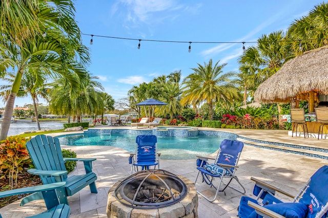 view of swimming pool with pool water feature, a gazebo, a water view, a patio, and an outdoor fire pit