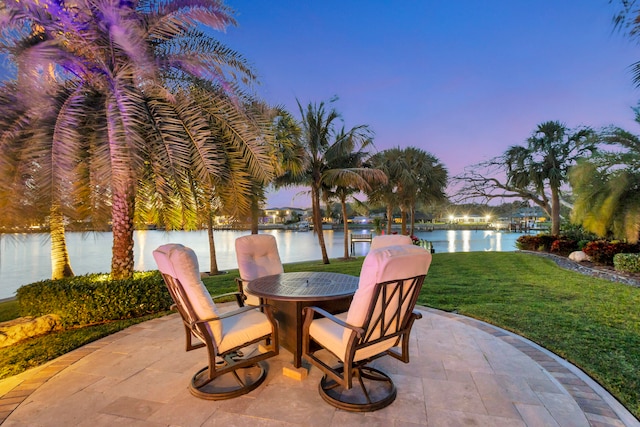 patio terrace at dusk with a yard and a water view