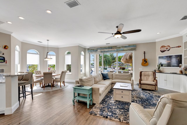 living room featuring ceiling fan, light wood-type flooring, and ornamental molding