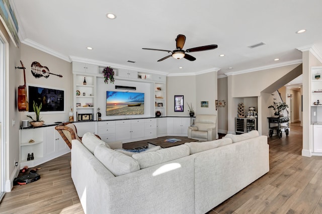 living room featuring ornamental molding, ceiling fan, built in shelves, and light wood-type flooring