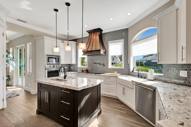 kitchen with stainless steel appliances, white cabinetry, pendant lighting, and light stone countertops