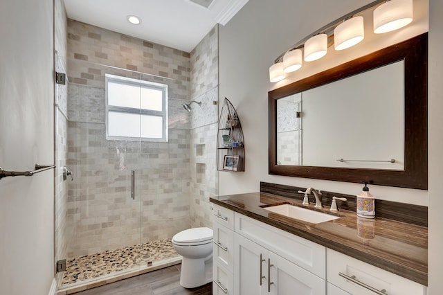 bathroom with toilet, hardwood / wood-style flooring, a shower with shower door, and vanity