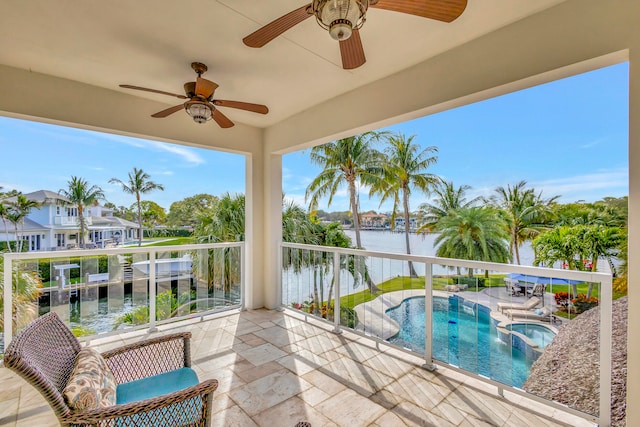 exterior space featuring a balcony, a swimming pool with hot tub, and a water view