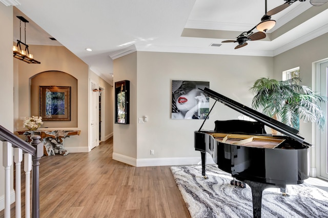 misc room with ceiling fan, light hardwood / wood-style floors, crown molding, and a tray ceiling