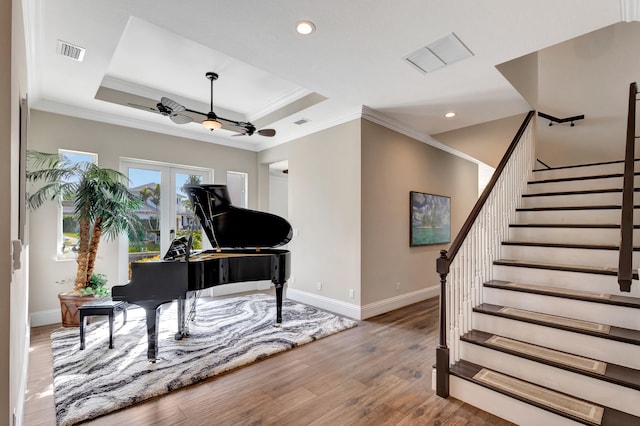 interior space with ornamental molding, a raised ceiling, and ceiling fan