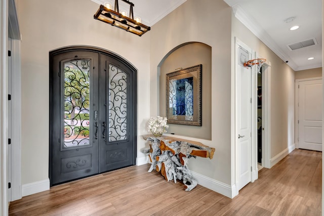 foyer featuring ornamental molding, french doors, and light hardwood / wood-style flooring