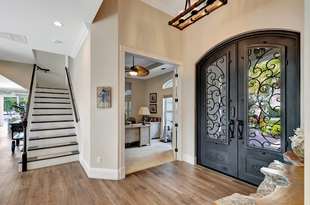 foyer featuring light hardwood / wood-style flooring, french doors, crown molding, and plenty of natural light