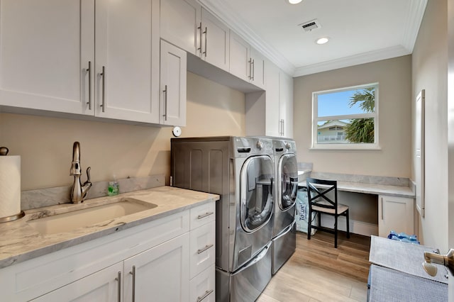 laundry room with sink, washing machine and dryer, ornamental molding, and cabinets