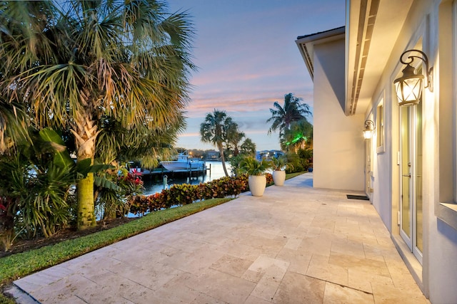 patio terrace at dusk featuring a water view