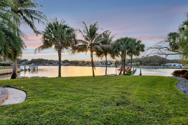 view of home's community featuring a dock, a yard, and a water view