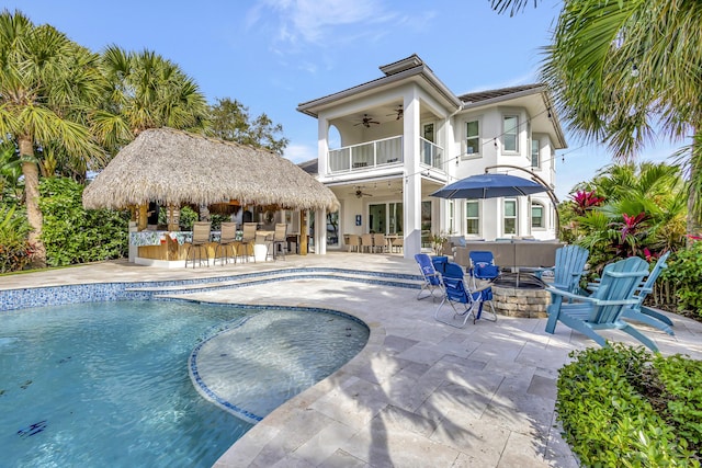 view of pool featuring an outdoor bar, a patio area, ceiling fan, and an outdoor living space with a fire pit