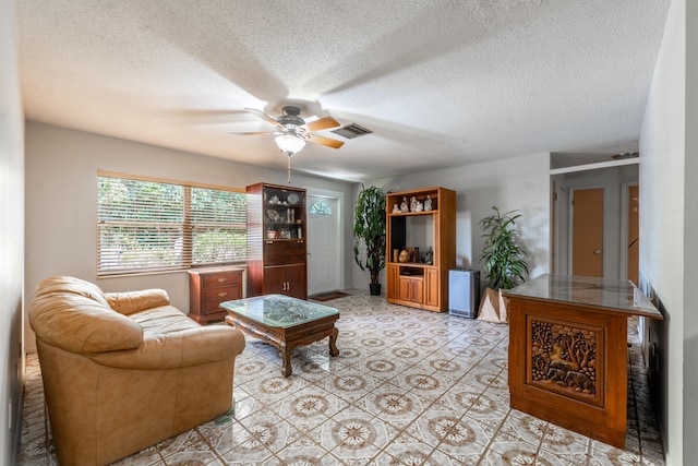 tiled living room with a textured ceiling and ceiling fan