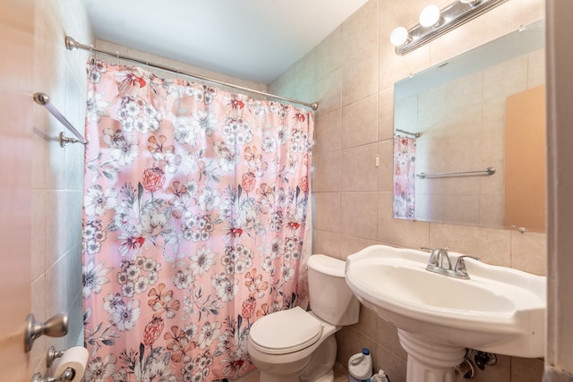 bathroom with toilet and tile walls