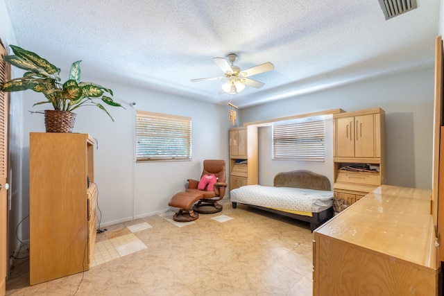 bedroom with light tile flooring, ceiling fan, and a textured ceiling