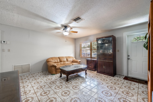 tiled living room with ceiling fan, a textured ceiling, and a wealth of natural light