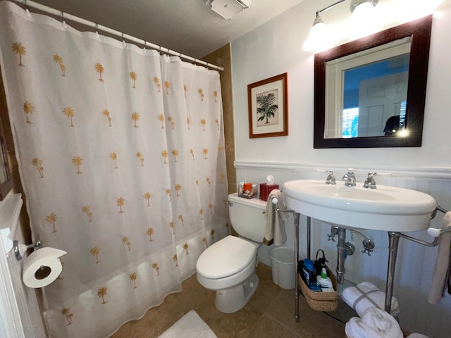 bathroom featuring tile patterned floors, shower / bath combo with shower curtain, and toilet