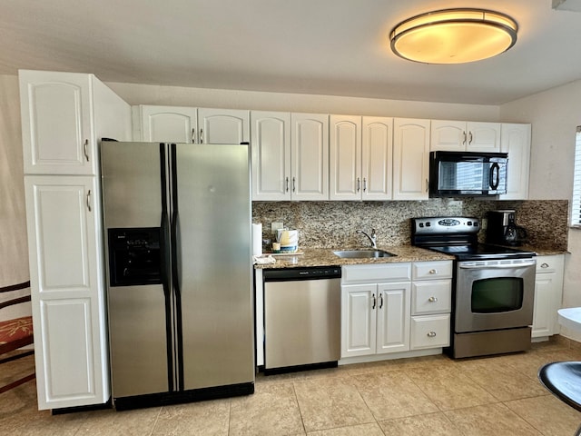 kitchen with white cabinetry, stainless steel appliances, dark stone counters, and sink