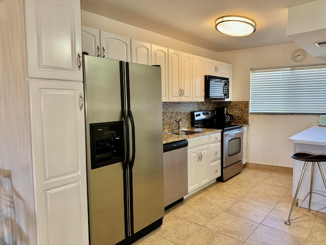 kitchen with sink, backsplash, stone countertops, white cabinetry, and appliances with stainless steel finishes