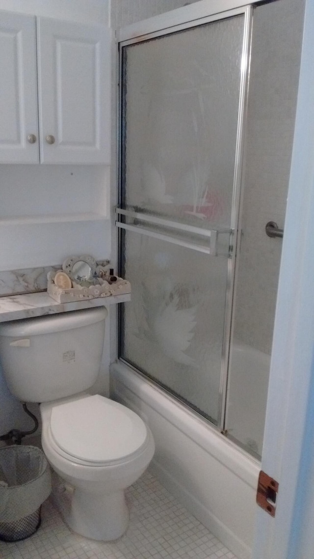 bathroom featuring enclosed tub / shower combo, toilet, and tile patterned flooring