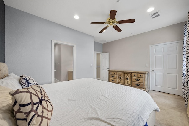 bedroom with light colored carpet, ensuite bathroom, and ceiling fan