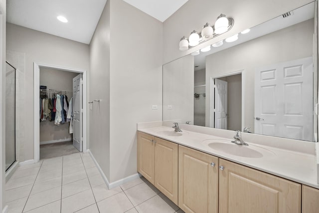 bathroom with a shower with door, dual sinks, large vanity, and tile flooring