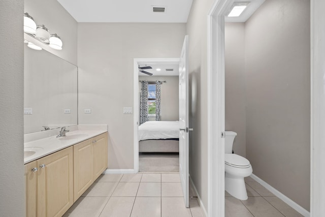 bathroom with toilet, ceiling fan, vanity with extensive cabinet space, dual sinks, and tile flooring