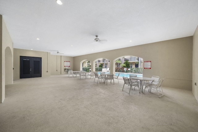 unfurnished dining area with light carpet, a textured ceiling, and ceiling fan