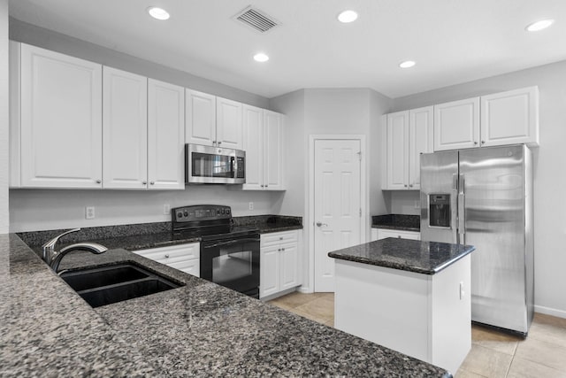 kitchen featuring sink, stainless steel appliances, dark stone countertops, a center island, and light tile floors