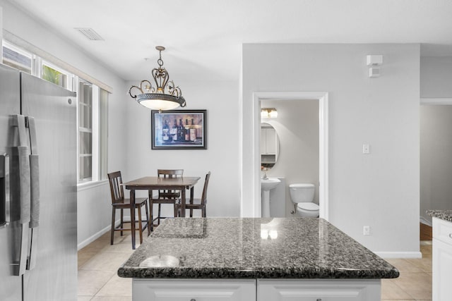 kitchen with pendant lighting, a center island, stainless steel refrigerator, and white cabinetry