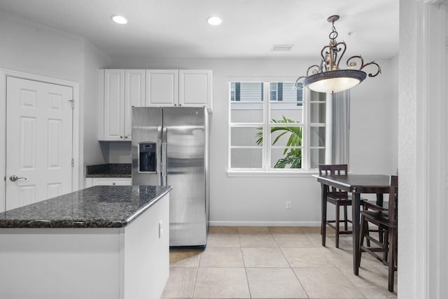 kitchen with stainless steel fridge, pendant lighting, light tile floors, white cabinets, and dark stone countertops