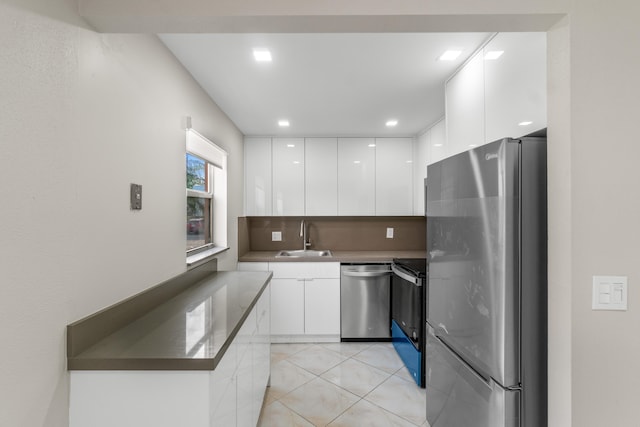 kitchen featuring sink, white cabinets, backsplash, stainless steel appliances, and light tile flooring