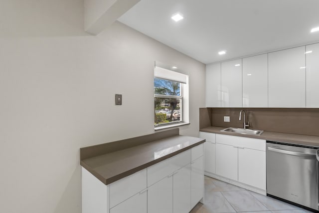 kitchen featuring light tile floors, white cabinetry, stainless steel dishwasher, and sink