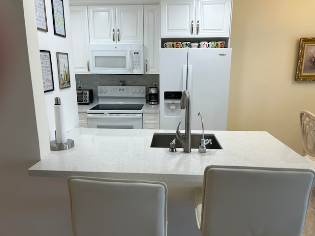 kitchen featuring white appliances, white cabinets, backsplash, and light stone counters