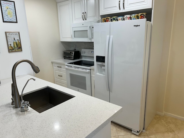 kitchen featuring white appliances, light stone counters, sink, and light tile floors