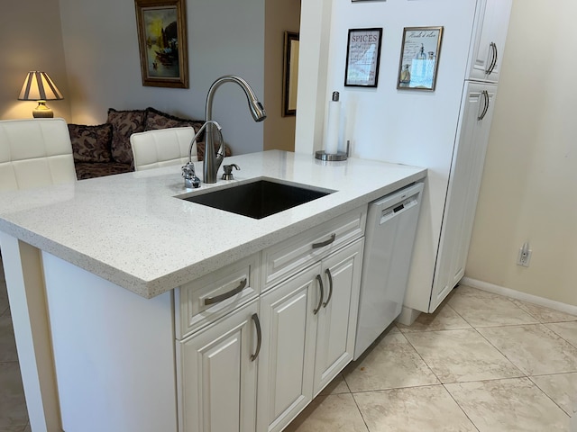 kitchen with sink, light tile floors, light stone counters, white cabinets, and dishwasher