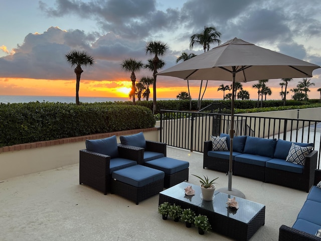 patio terrace at dusk featuring a balcony, outdoor lounge area, and a water view