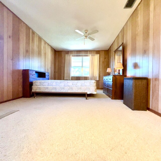 unfurnished bedroom with wood walls, light colored carpet, and ceiling fan