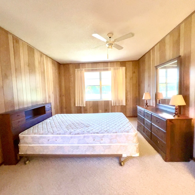 carpeted bedroom with wooden walls, multiple windows, and ceiling fan