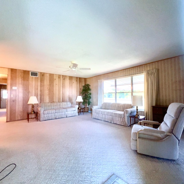 unfurnished living room with ceiling fan, wood walls, and carpet