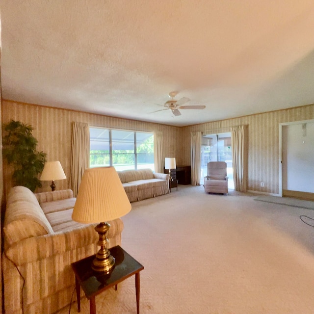 living room with a textured ceiling, light colored carpet, and ceiling fan