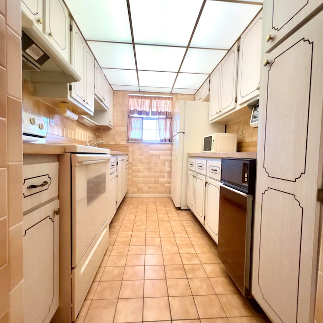 kitchen featuring light tile flooring, white appliances, and white cabinets