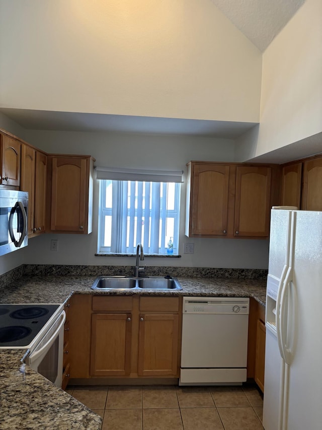 kitchen featuring sink, light tile patterned floors, vaulted ceiling, and white appliances